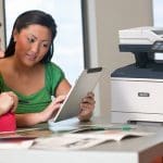 Xerox® VersaLink® B415 Multifunction Printer en situation au travail Deux femmes utilisant une tablette devant une imprimante multifonction Xerox® VersaLink® B415