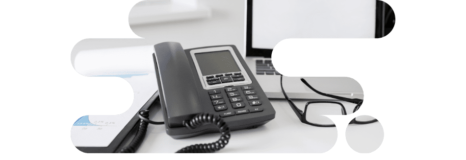 Poste de travail équipé d'un téléphone fixe et d'un ordinateur portable, illustrant la convergence fixe-mobile entreprise et l'unification des communications.